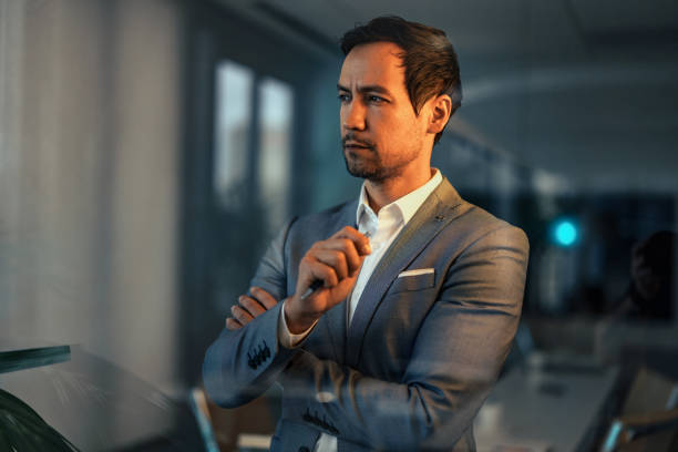 istock Contemplative Asian Businessman in Moody Lighting 2195255176