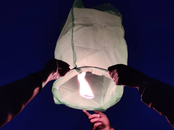 istock Person lighting up a paper lantern in the air 2195256069