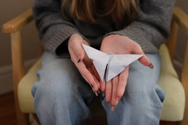 A Young woman is holding a paper butterfly she made herself
