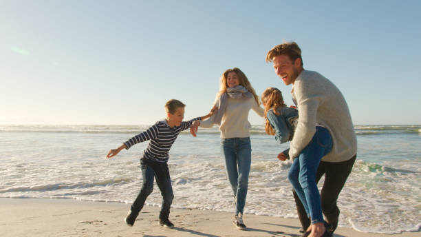 istock Family On Winter Beach Running Away From Advancing Waves 2195261705