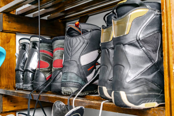 istock Snowboard boots, standing on customized wooden wall mount at warehouse for seasonal storage at ski alpine resort. Extreme winter sport equipment handling at home 2195261830