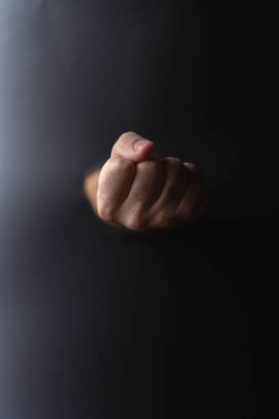 Close up of a woman's fist against a blurry face background