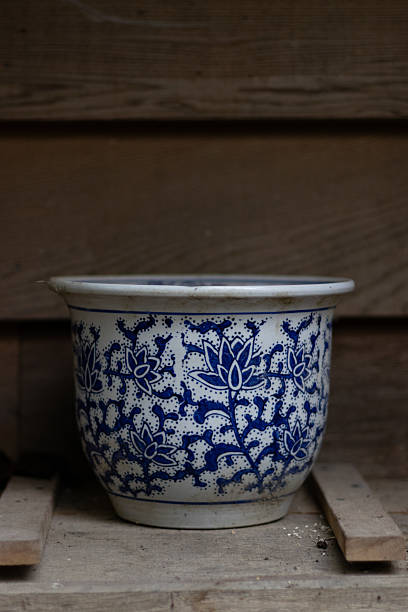 istock A close-up view of a vintage ceramic pot adorned with delicate blue floral patterns, set against a rustic wooden backdrop. 2195269234