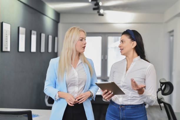 istock Dedicated Businesswomen Chatting in Office While Looking at Digital Reports on Tablet 2195272021