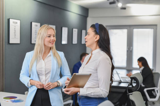 istock Beautiful Female Colleagues Discussing Project Updates in Modern Office 2195272646