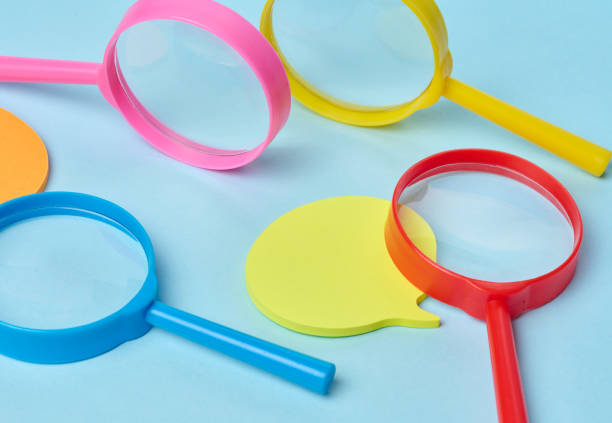istock Multicolored plastic magnifying glasses on a blue background and paper notes 2195279409
