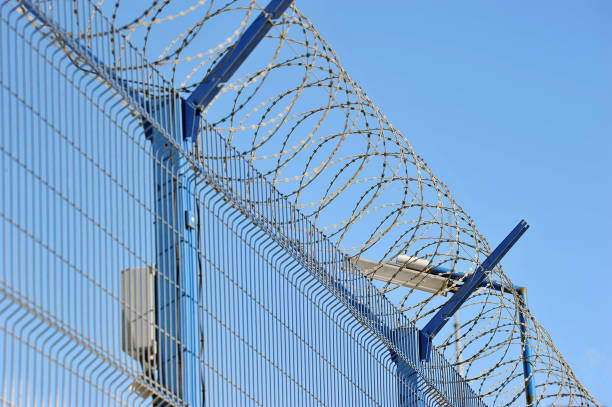 istock barbed wire on the fence of a protected facility 2195281511