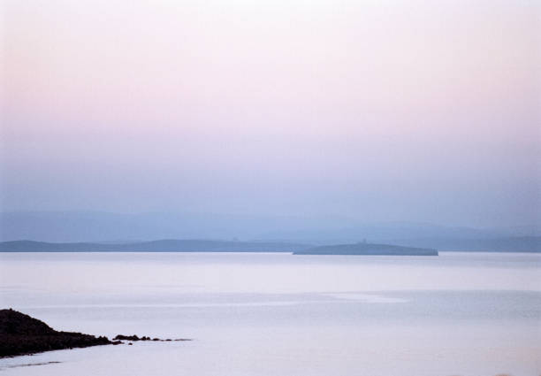 Detail of the coastline at sunrise at a small fishing village at the eastern part of the Greek Island of Chios in the Aegean Sea on a sunny midday in spring (late March). In the background is the Turkish coastline. The image was captured on old-fashioned 35mm daylight ISO 200 film by an analogue (or analog) 35 mm film camera. The granularity in the image is real film grain (due to the presence of small particles of dyed silver halide on the negative). Minimal post processing has been done (only adjustment of histogram). The image is part of a series of the landscape on the Greek Island of Chios.