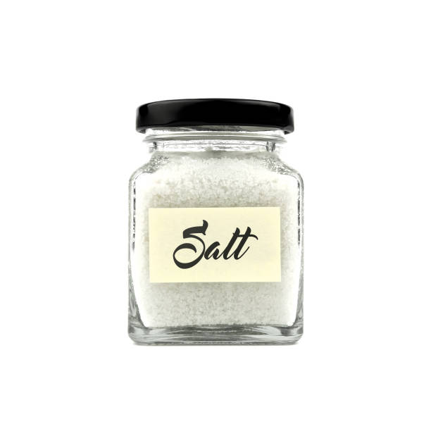 istock Salt in a glass bottle isolated on white background, with word SALT on yellow stick note paper and black lid. Modern and stylish. Close up. 2195283823