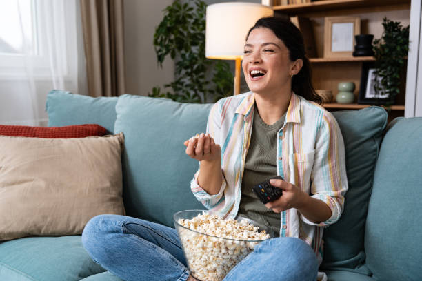 istock Young happy freshly divorced or recently single woman after toxic relationship breakup sitting alone at home on sofa, eating popcorn and watching movie or television in her new apartment she rented. 2195286236