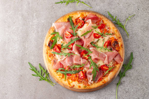 istock Pizza with prosciutto, ham, arugula, spinach, tomatoes, pesto, cheese and parmesan. Italian cuisine 2195286903