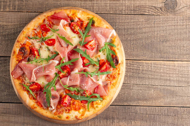 istock Pizza with prosciutto, ham, arugula, spinach, tomatoes, pesto, cheese and parmesan. Italian cuisine 2195286931