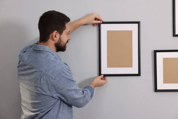 istock Man hanging picture frame on gray wall 2195288408