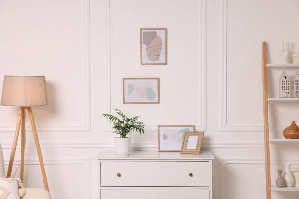 istock Picture frames hanging on white wall and chest of drawers at home 2195288428
