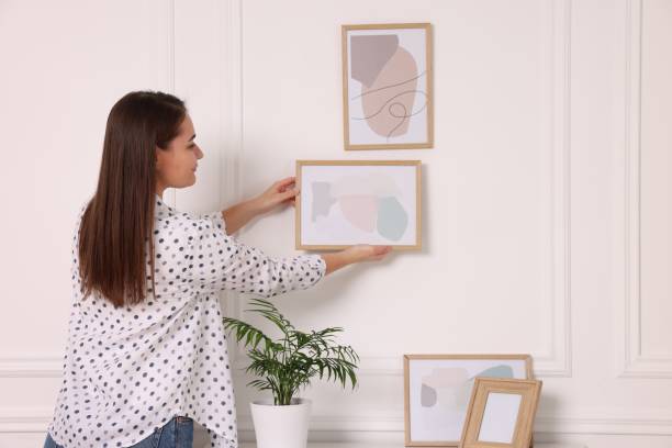 istock Woman hanging picture frame on white wall at home 2195288432
