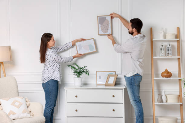 istock Man and woman hanging picture frames on white wall at home 2195288460