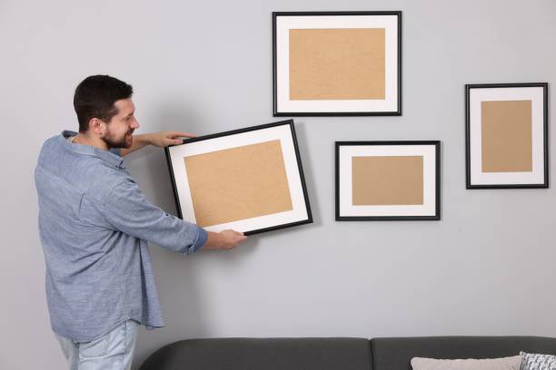 istock Man hanging picture frame on gray wall indoors 2195288463