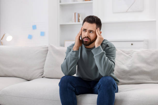 istock Man suffering from headache on sofa at home 2195288479