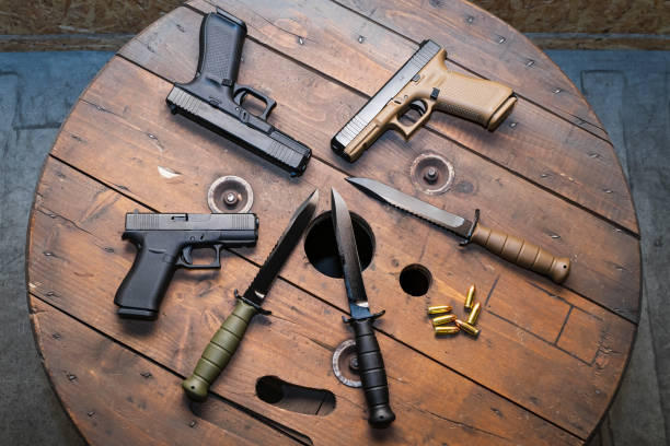 istock Modern pistols and army knives on a wooden surface. 2195290493