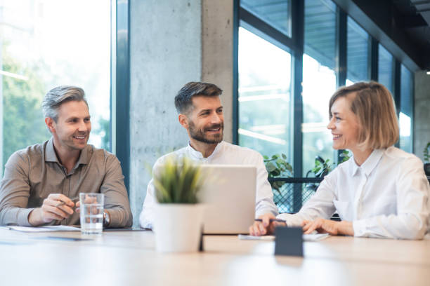 istock Three business people discussing work together using a tablet and laptop taking notes in a modern office 2195291362