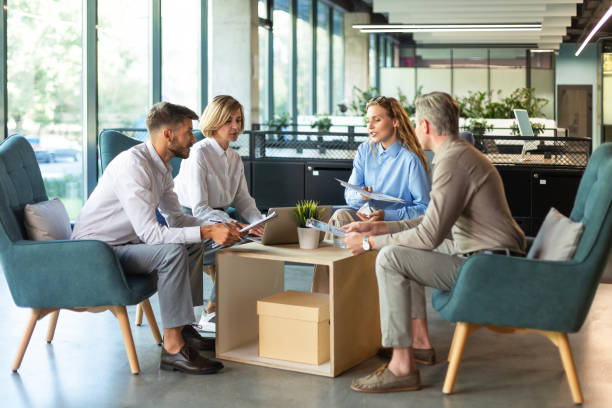 istock Handsome man gesturing and discussing something while his coworkers listening to him sitting at the office table. 2195291540