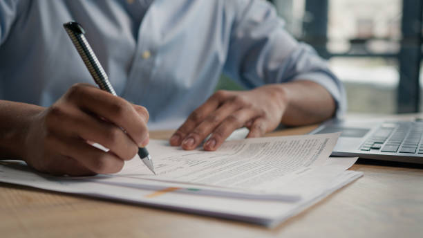 istock Close up unrecognizable man businessman writing paperwork report on desktop male hands signing business documents on office table student write educational test english exam studying in university 2195300935