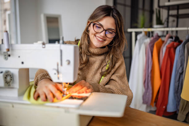 istock Seamstress works on a vibrant fabric project inside a bright workshop with colorful garments hanging in the background 2195302091