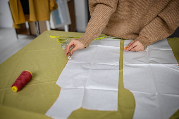 istock Woman cutting fabric patterns in a creative workspace during the daytime 2195303596