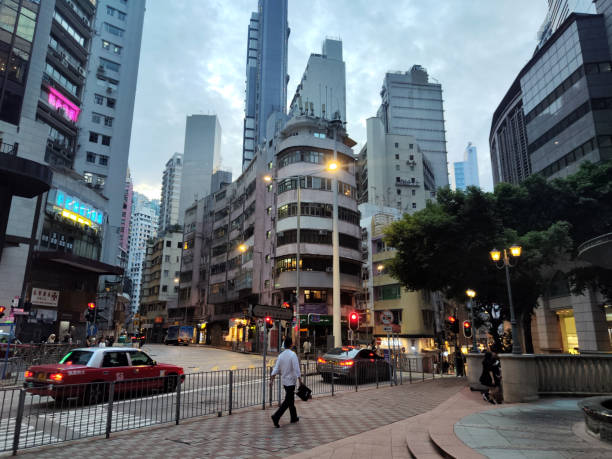 People walking on Queen's road, at an old traditional corner building, Sheung Wan, Hong Kong Island.