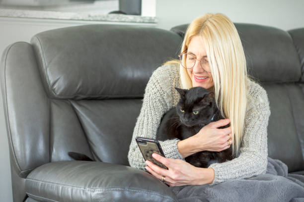 istock Woman on Couch With Black Cat Taking Selfie 2195307784