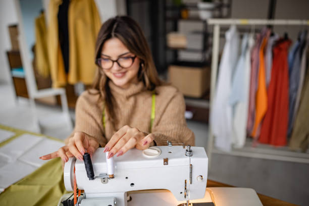 istock Woman sewing in a creative workspace surrounded by colorful fabrics and garments during daylight hours 2195309087