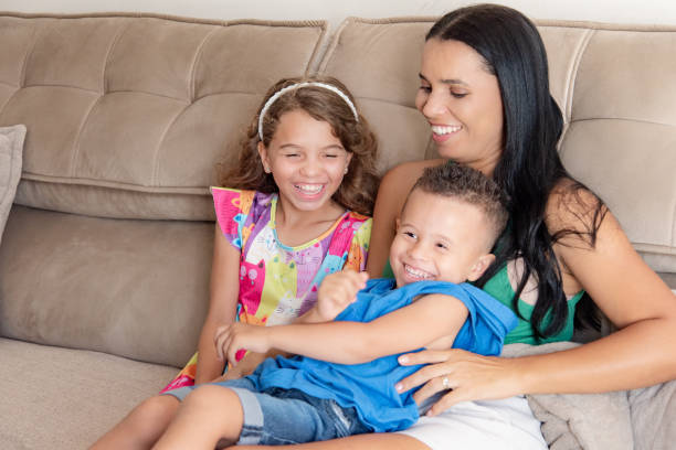 istock mother with two children tickling on the sofa 2195309705