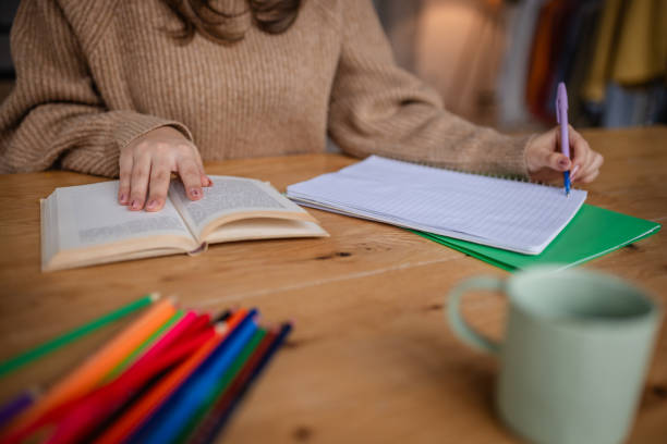 istock Woman studying at home with open book and notebook filled with notes during a cozy afternoon 2195309794