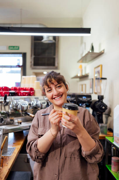 istock Smiling barista writing name on takeaway coffee cup in cafe 2195310560