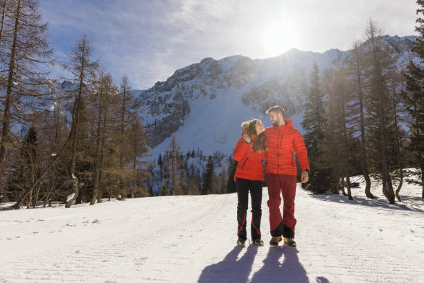Young loving couple walks in the snow with snow-capped mountains in background
