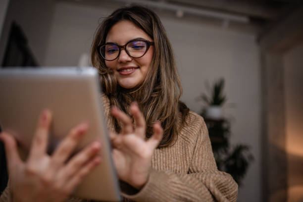 istock Young woman using a tablet and smiling in a cozy indoor setting at dusk 2195314562