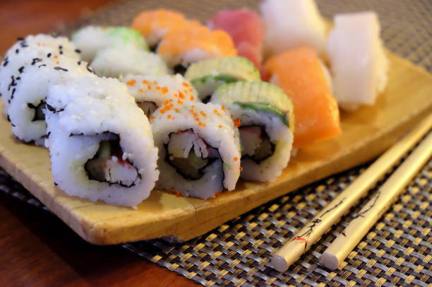 Wooden board with sushi rolls and sticks, in an asian restaurant