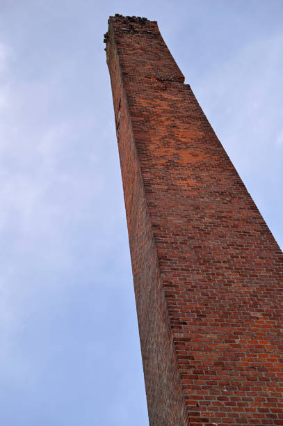 istock Square brick chimney from an old abandoned factoryf against blue sky 2195317653