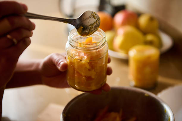 istock Person preserving sliced fruit in jars in a bright kitchen setting 2195321381
