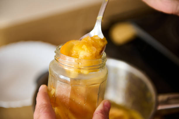 istock Hands Filling a Jar with Homemade Preserved Fruit Using a Spoon 2195321382