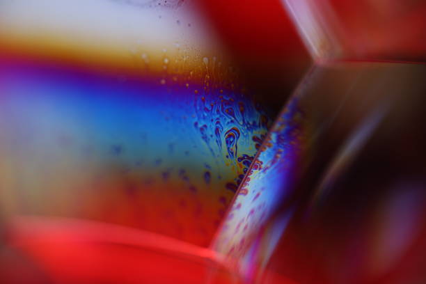 Red liquid surface in the darkness, bright fluid background, smooth movement, rainbow reflection