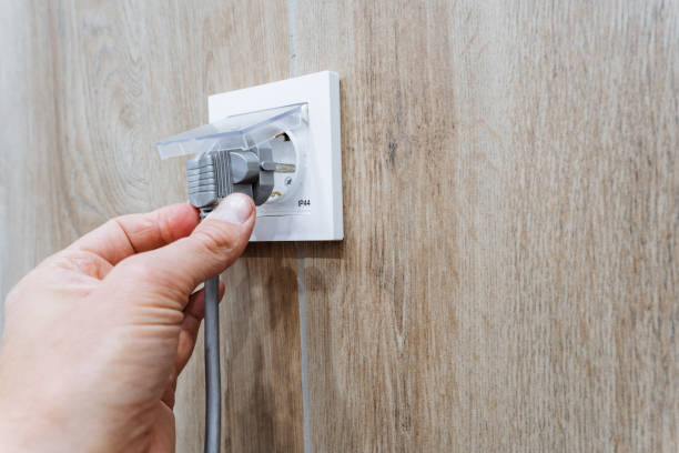 istock A person is carefully plugging a cord into an outlet, which is a common and routine action in modern households as they connect various devices to power sources for functionality 2195328460