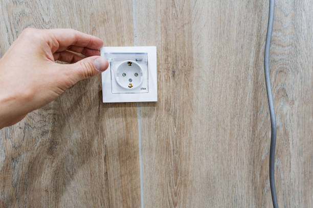 istock A person is skillfully plugging a cord into an electrical outlet that is located on a beautifully finished wooden wall, demonstrating a common everyday action involving electricity 2195328493