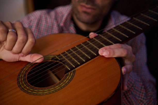 istock Person playing acoustic guitar and plucking the strings with hands close up 2195329100