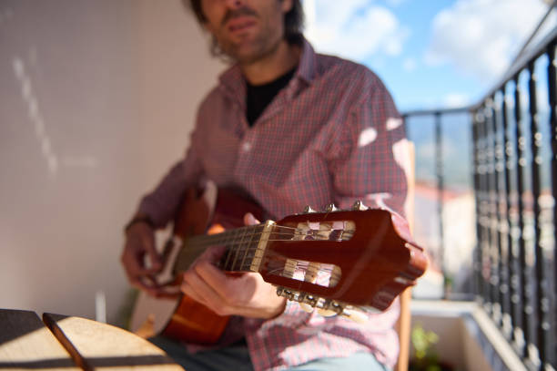 Man playing guitar on a balcony with a relaxed atmosphere