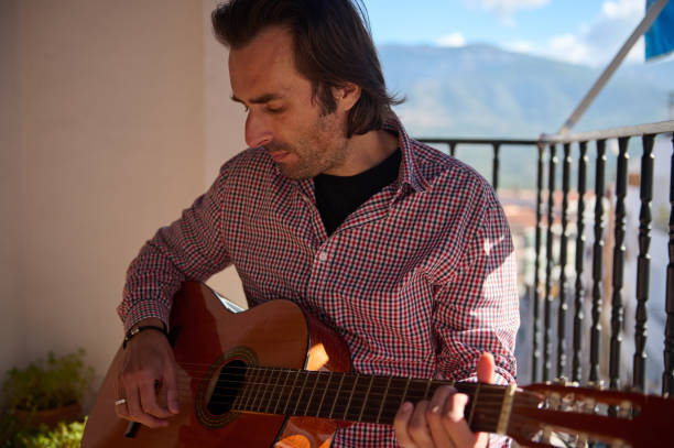 istock Man with a guitar plays music on a balcony with a scenic view 2195329154