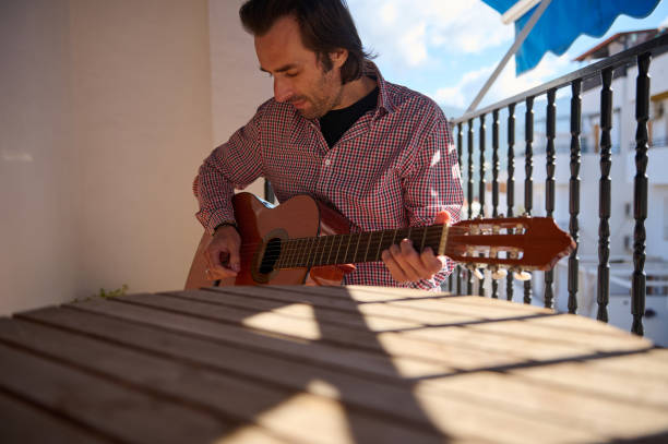 istock Man playing acoustic guitar on a sunny balcony during the day 2195329163
