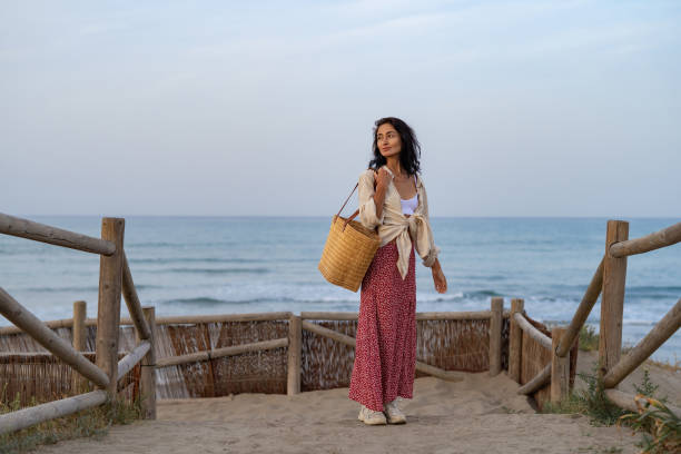 A beautiful brunette in a red skirt walks on the beach