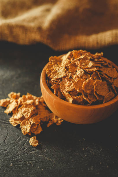 istock A wooden bowl filled with crunchy breakfast cereal flakes on a dark surface with rustic fabric in the background. Perfect for illustrating breakfast or healthy eating concepts 2195333005