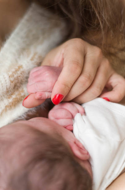 Young mother breastfeeding newborn baby.
